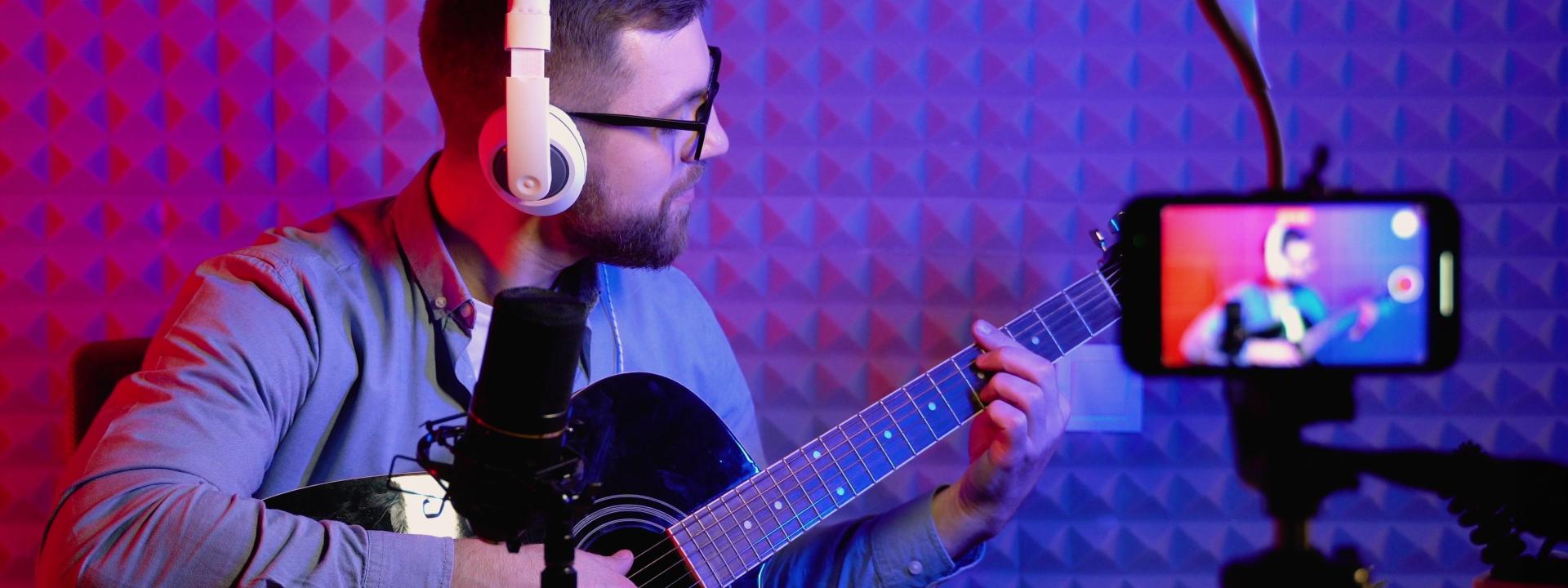 Man met gitaar in muziekstudio